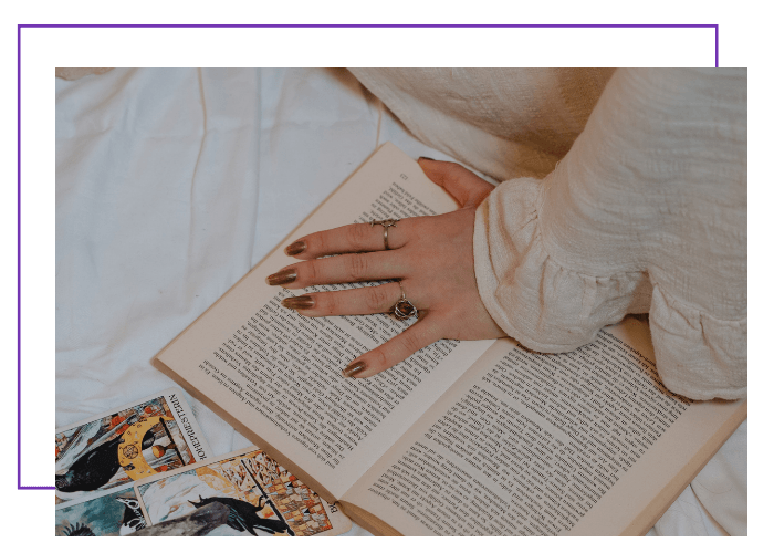 Eine junge Frau hat ein Buch auf dem Bett aufgeschlagen und informiert sich über die Bedeutung der Engelzahl 444